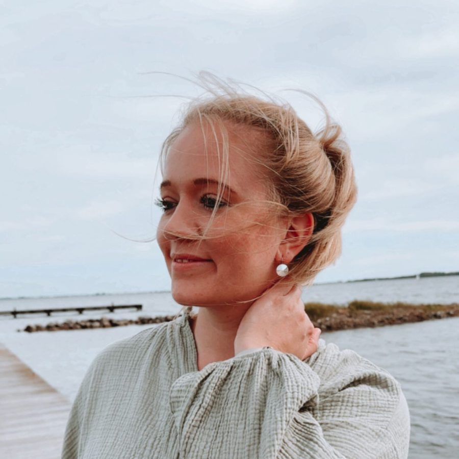 Life Coach Sophia steht entspannt am Meer, lächelt sanft und strahlt Ruhe aus – ganzheitliches Coaching für mehr Selbstbestimmung, Resilienz & Lebensfreude